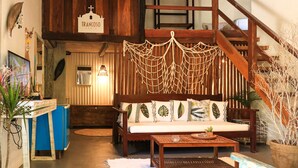 Una habitación acogedora con una escalera de madera, un sofá con cojines de estampado floral y una decoración de macramé colgante.