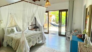 Un dormitorio con cama con dosel, techo de madera, un ventanal y vistas a la vegetación exterior.