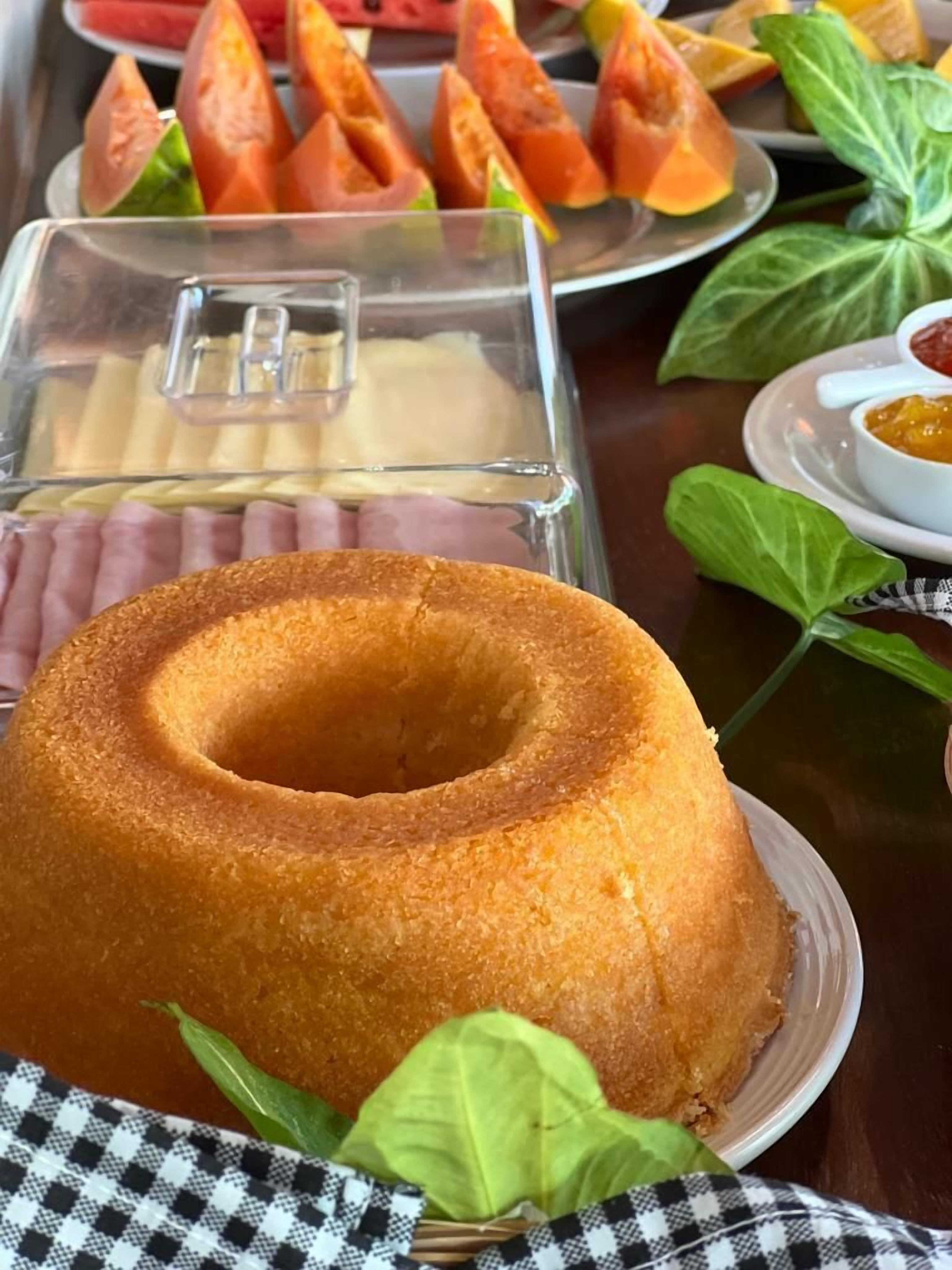 A dessert table with a bundt cake, fruit slices, and a cheese platter.