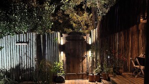 Una terraza de madera con plantas en macetas y un portón rústico.