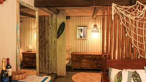 Una habitación rústica con techo de madera, un banco de madera, un tapiz tejido y un letrero sobre el banco que dice "FRANCOSO BAHIA".