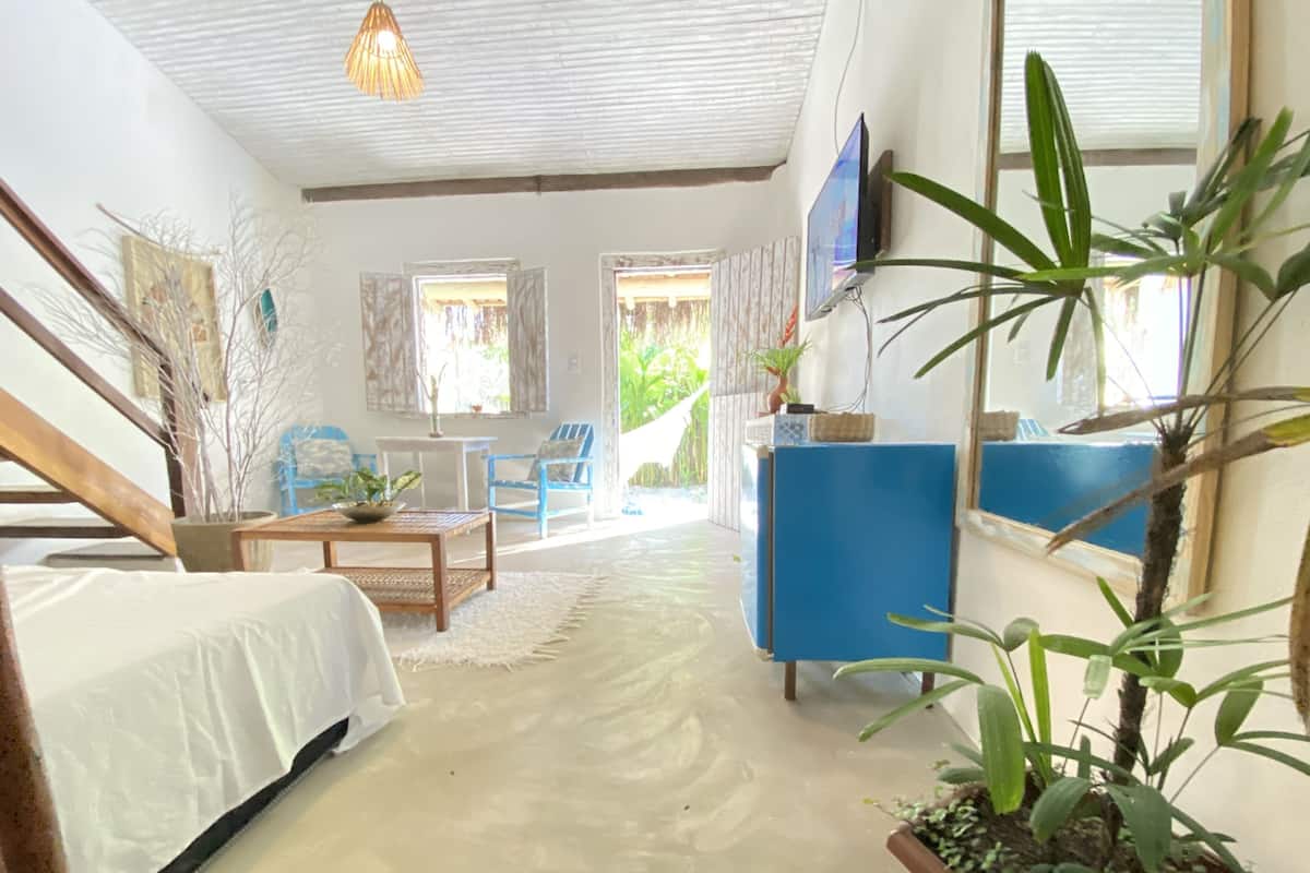 A room with a bed, a desk, a chair, a TV, and a plant.