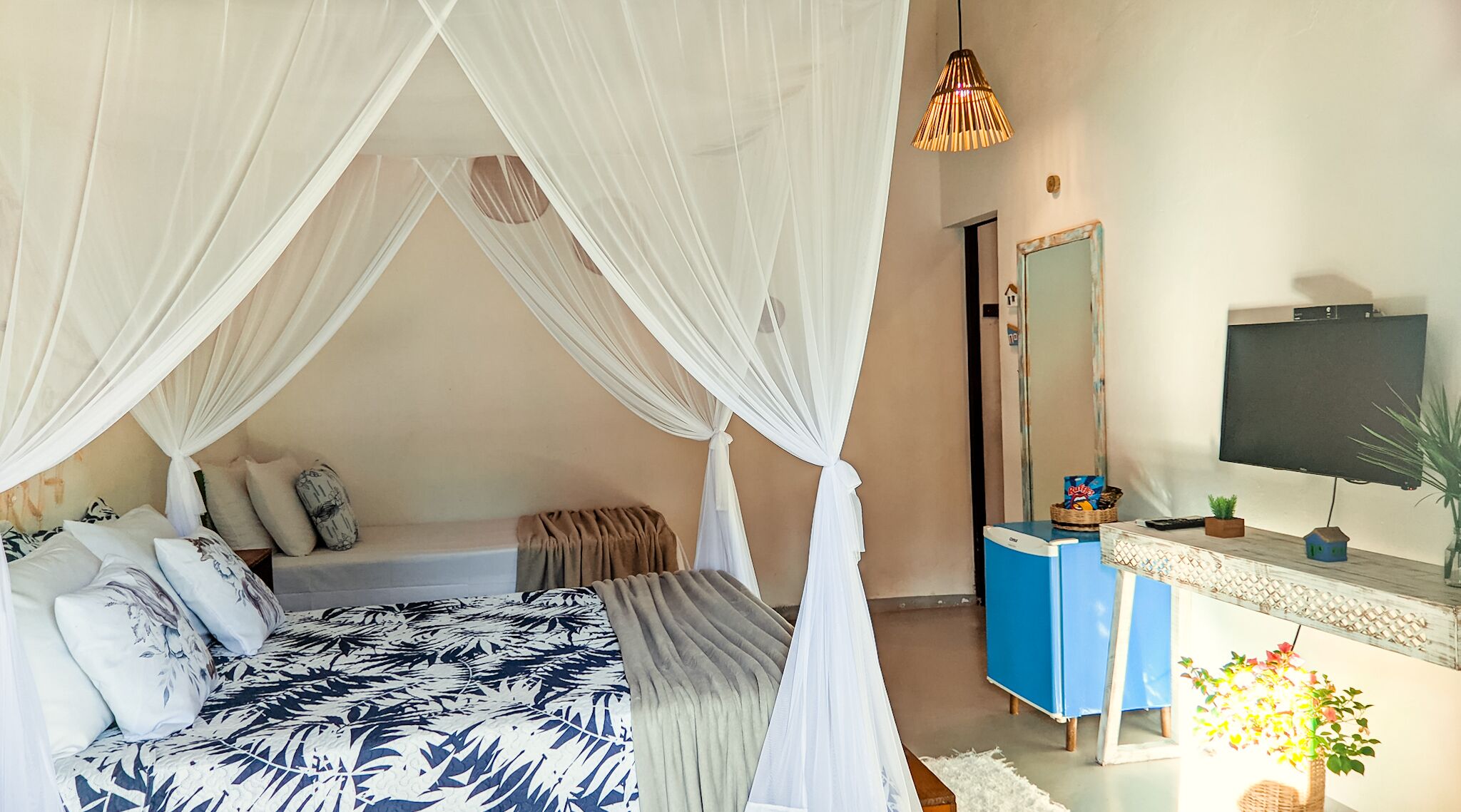A bedroom with a canopy bed, a TV, and a small plant.