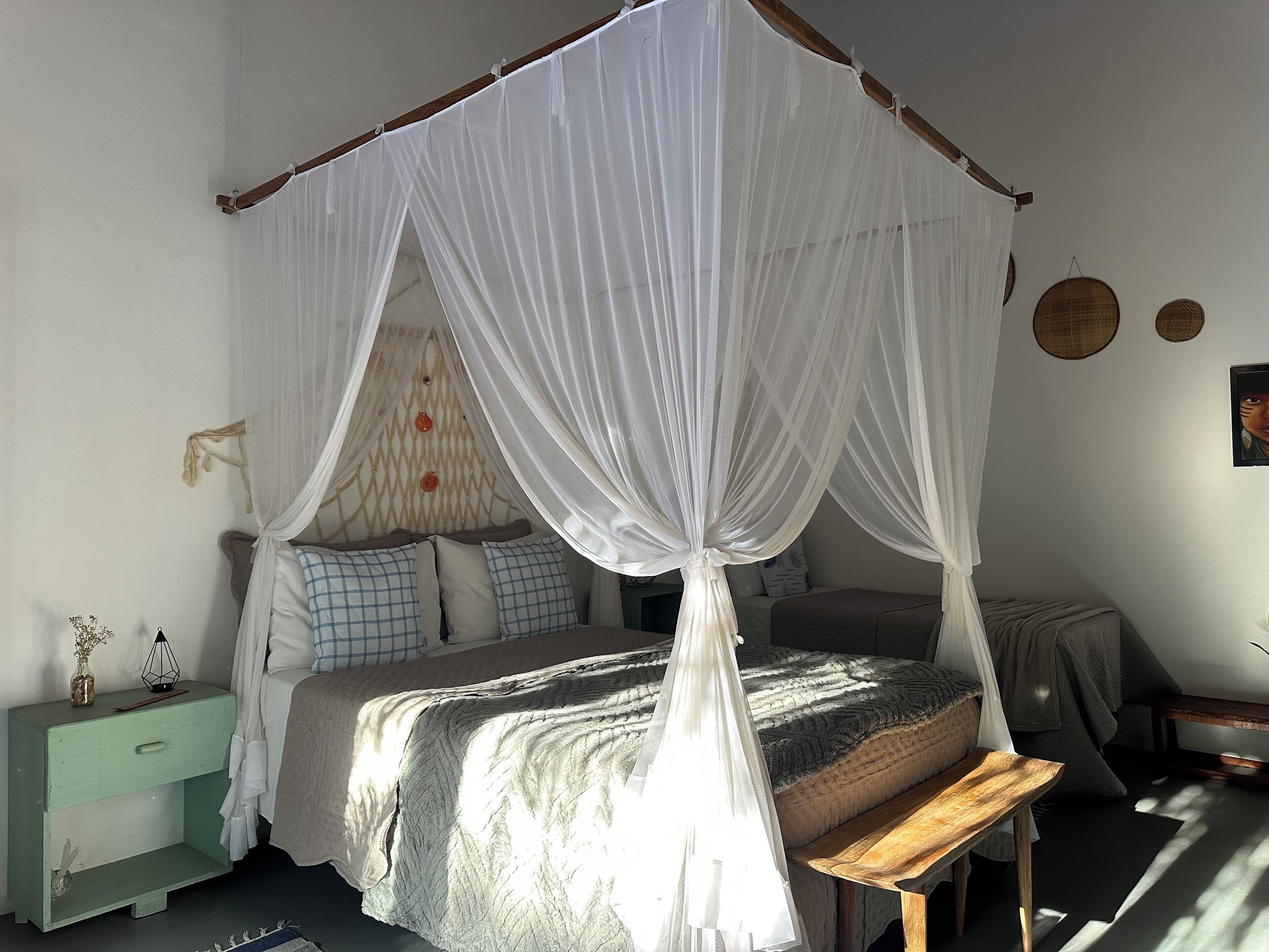 A bedroom with a canopy bed, a bedside table, a nightstand, and a wall-mounted lamp.