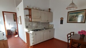 Una cocina compacta con armarios blancos, salpicadero de azulejos y una lámpara colgante.