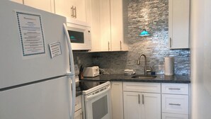 A modern kitchen with white cabinets, a microwave, a toaster, and a sink.