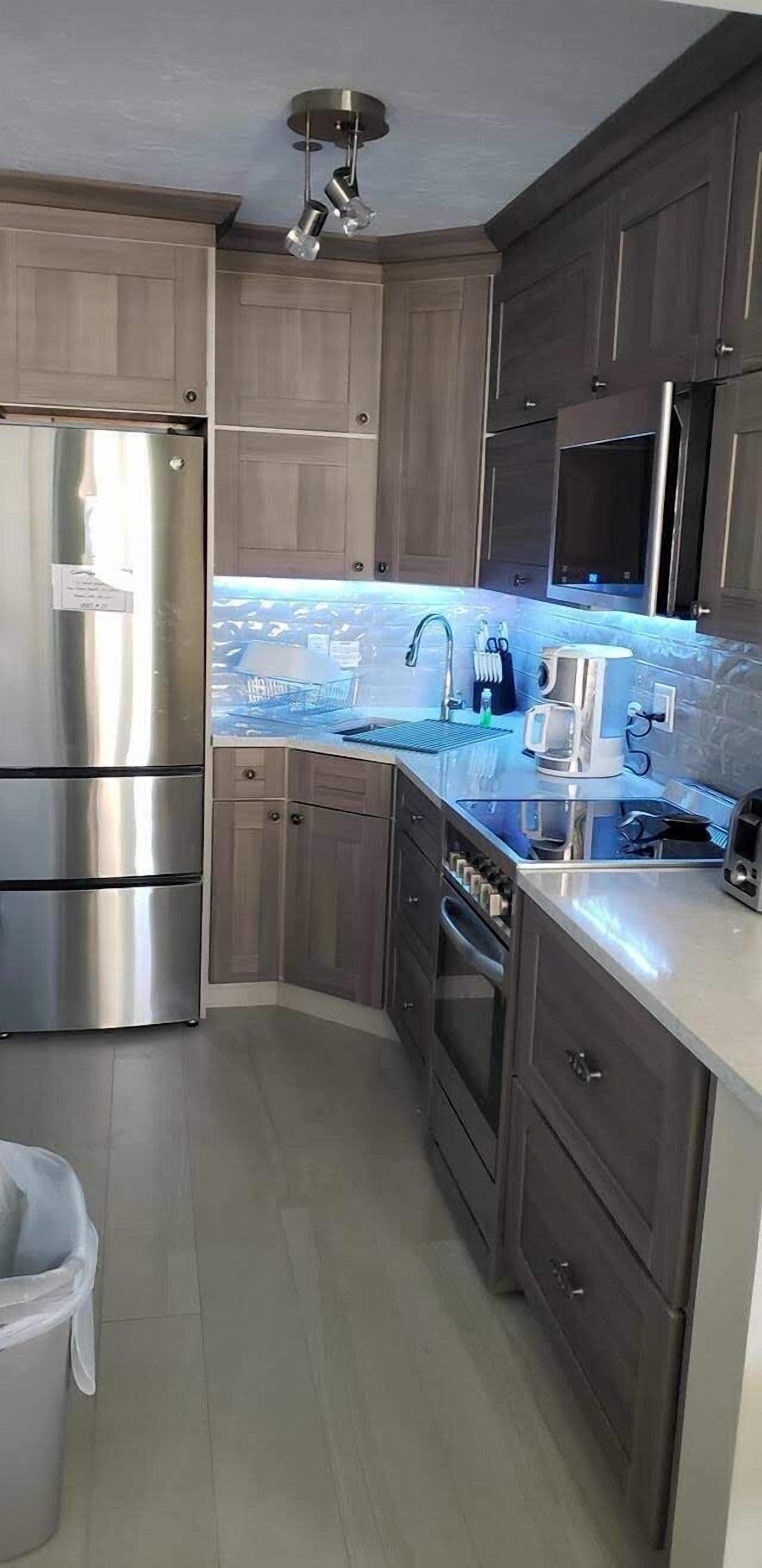 A modern kitchen with dark wood cabinets, stainless steel appliances, and a built-in microwave.