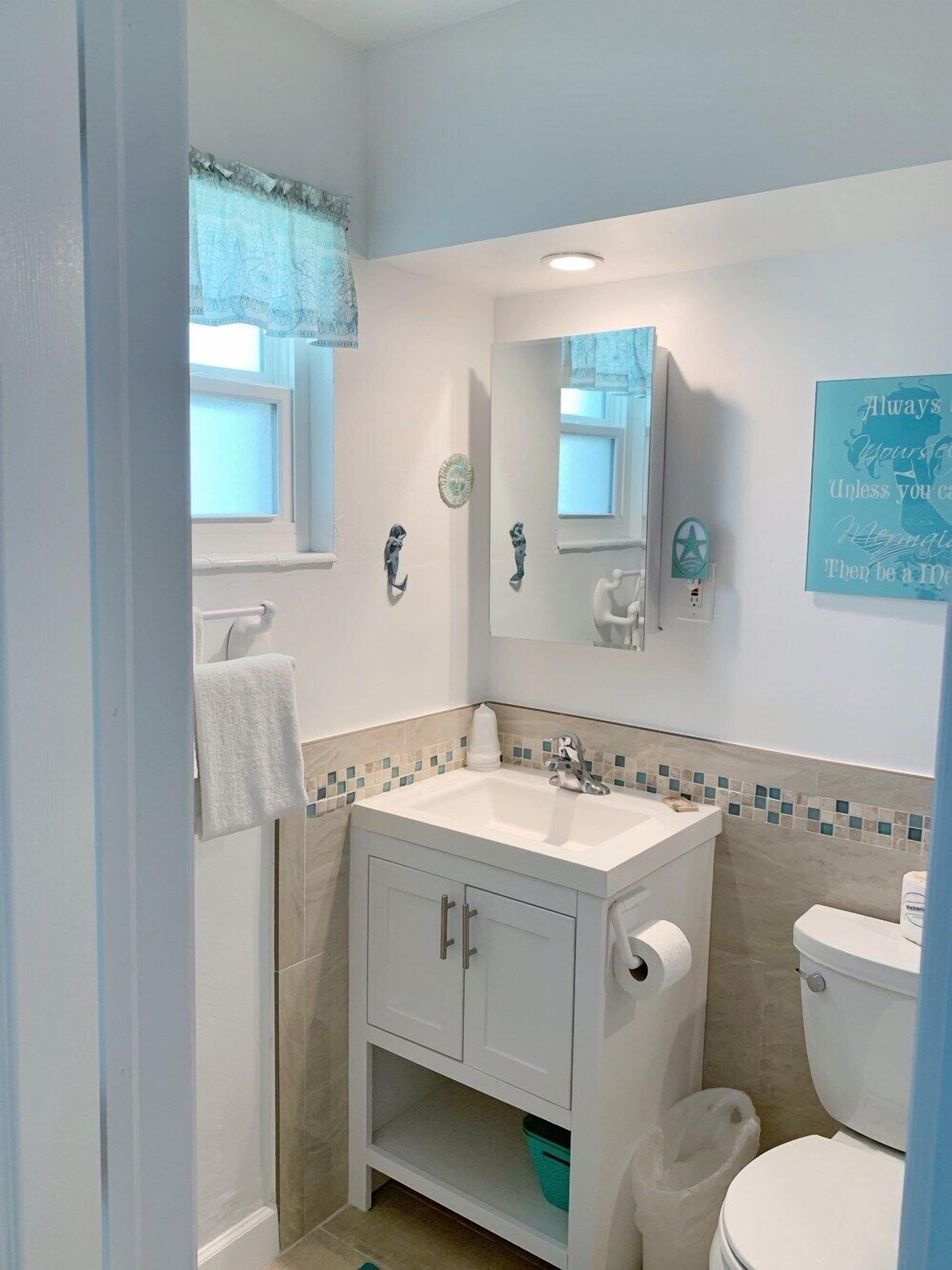 A bathroom with a white sink, a mirror, a toilet, and a towel rack.