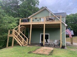 A two-story house with a wooden deck, outdoor seating, and an American flag. - Welcome to our lake house in this "tranquil cove" on Lake Chatuge (Hiawassee)