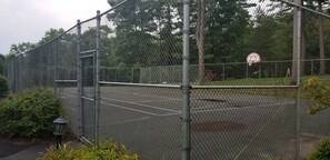 A chain-link fence surrounding a basketball court with a basketball hoop and a sign indicating no ball bounce. - Lake View, Beautiful Condo, Private Beach and Pool (Bolton)
