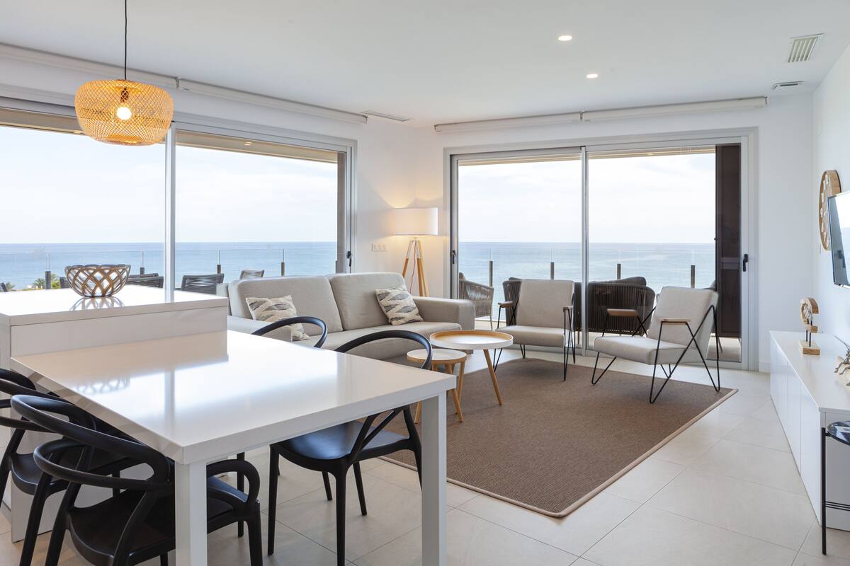 Ein modernes Wohnzimmer mit Essbereich, großen Fenstern und Meerblick.