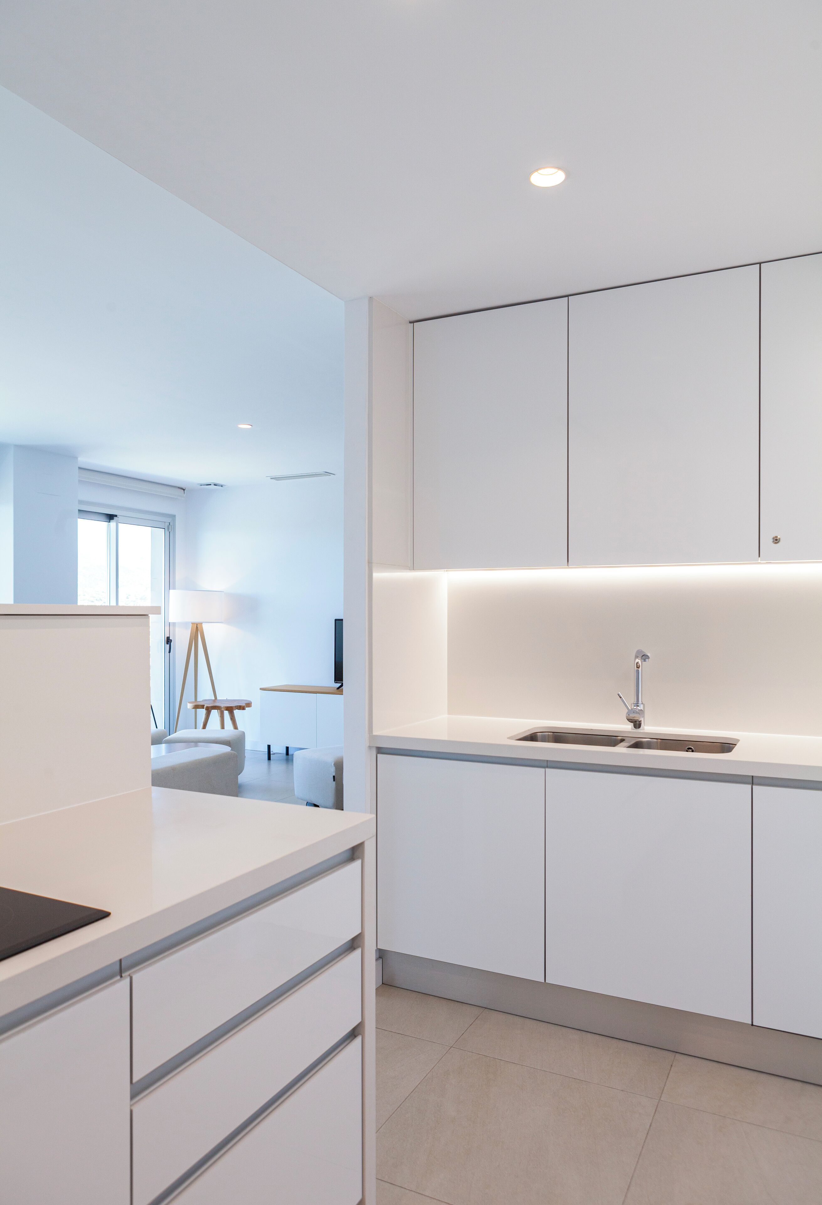 Una cocina moderna con armarios blancos, un lavamanos integrado y una pequeña mesita.