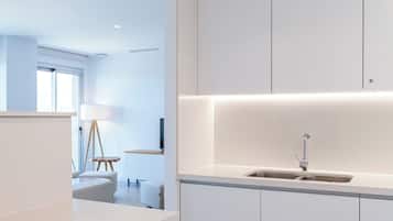 Una cocina moderna con armarios blancos, un lavamanos integrado y una pequeña mesita.