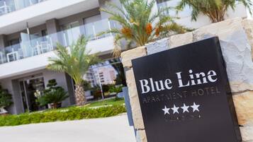 Ein Schild für das Blue Line Apartment Hotel mit einem modernen Gebäude im Hintergrund.