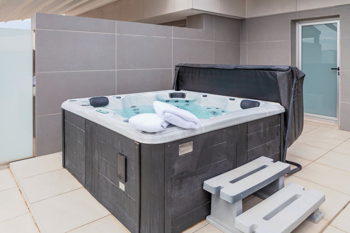 Ein Whirlpool mit Abdeckung, einem Handtuch und einem Stufe für den Zugang.