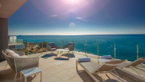 Een balkon met uitzicht op zee, voorzien van stoelen en een tafel.