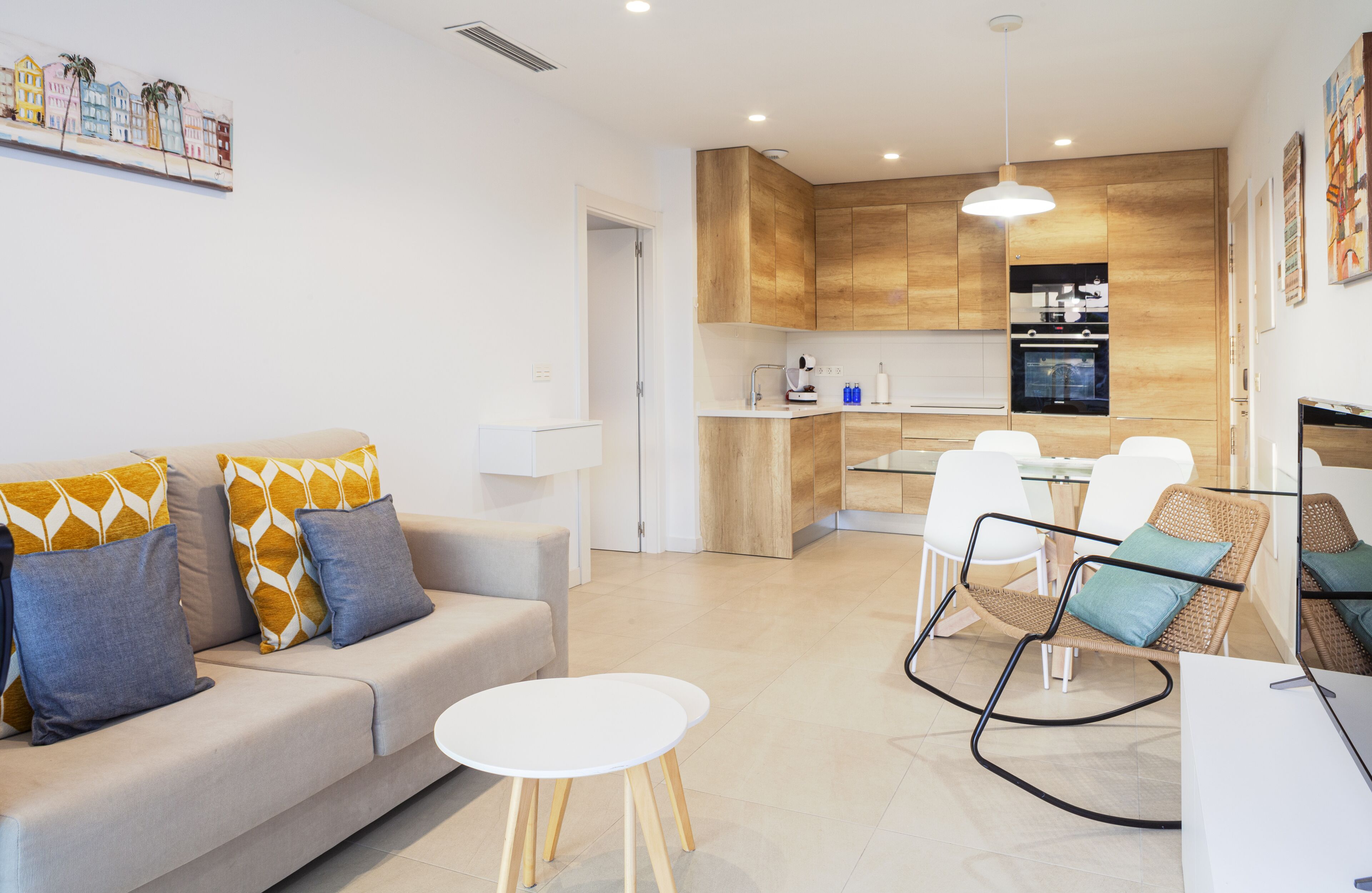 Una sala de estar moderna con un sofá, una mesa redonda y una silla de mimbre.