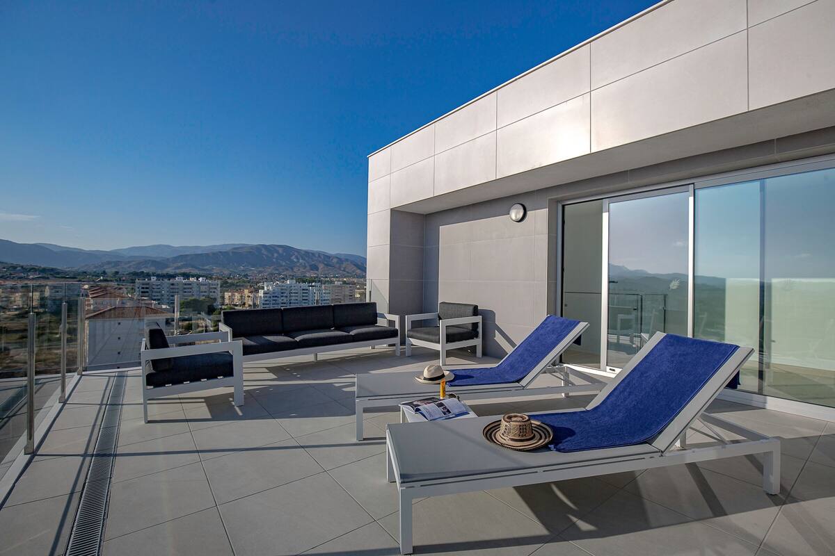 Eine Dachterrasse mit Liegestühlen, einer Sitzecke und einem Esstisch.