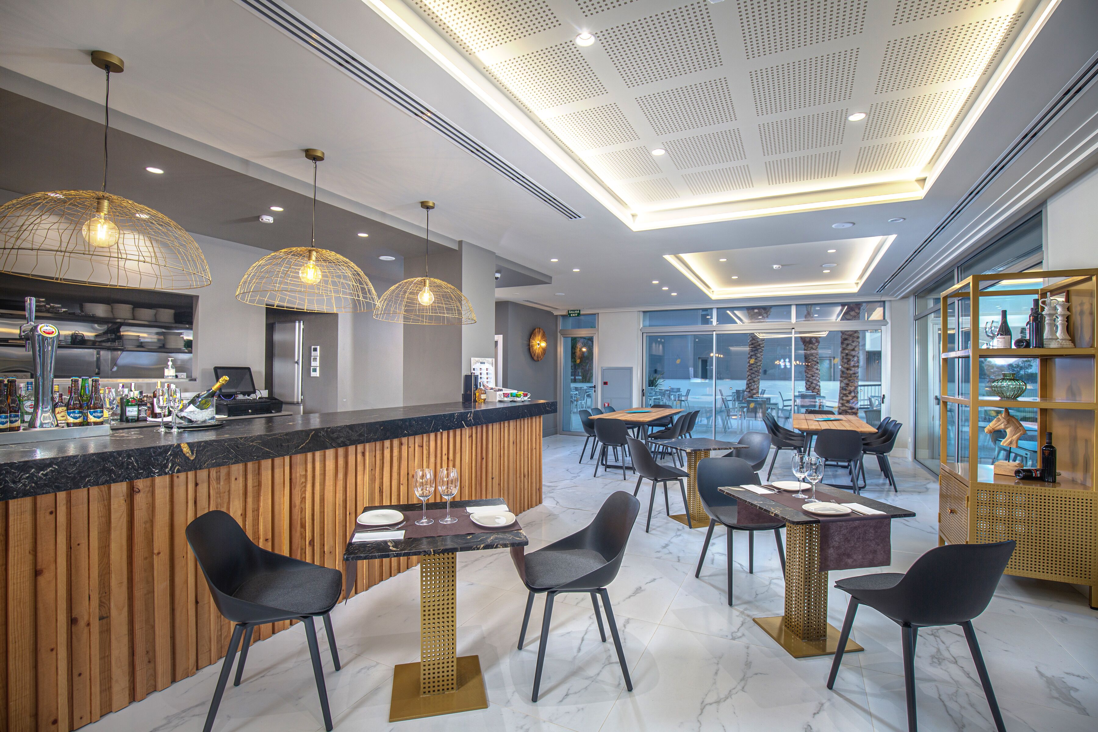 A modern restaurant with a bar area, wooden accents, and contemporary lighting fixtures.