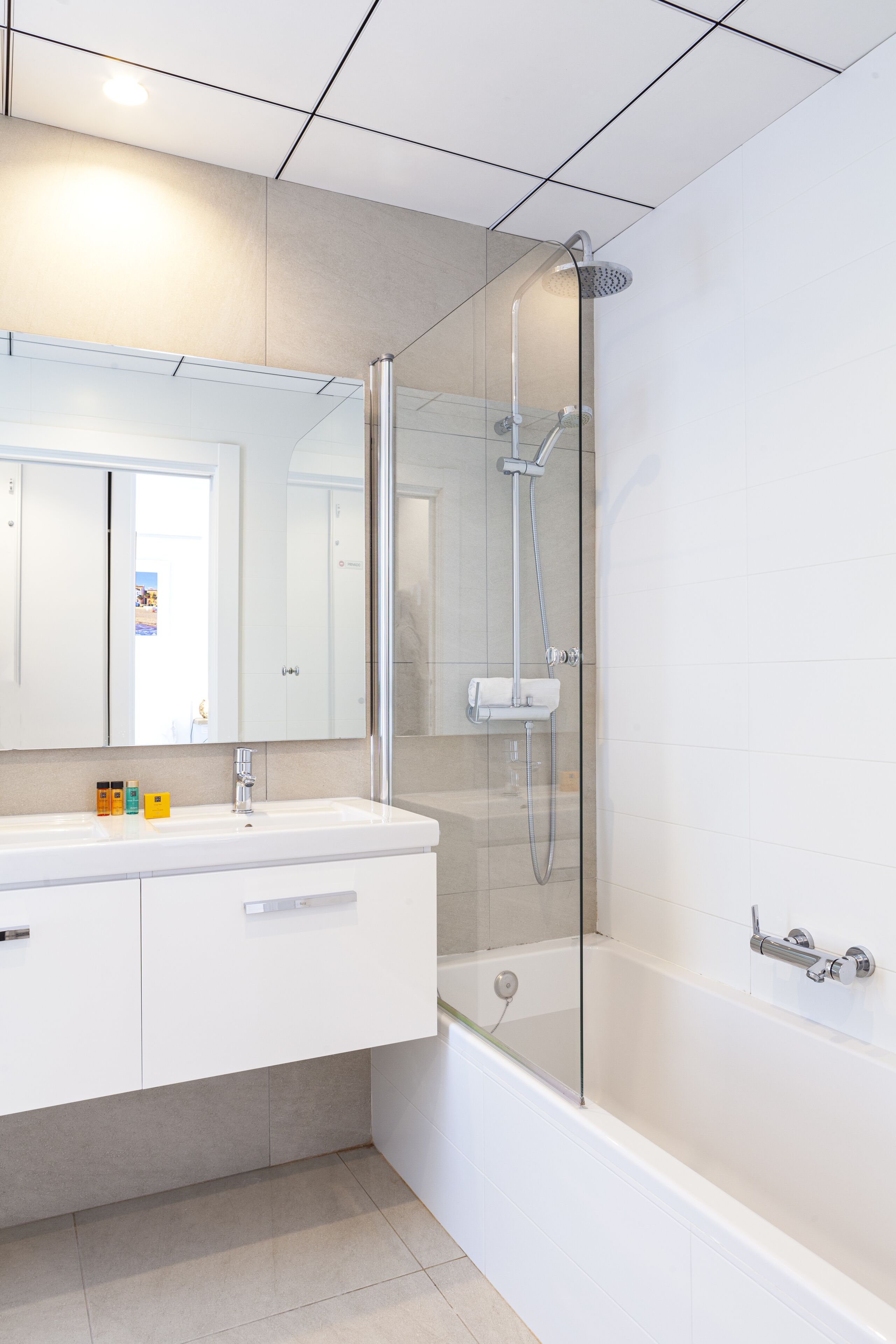 A modern bathroom with a glass-enclosed shower, a white vanity with a mirror, and a bathtub.