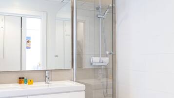 A modern bathroom with a glass-enclosed shower, a white vanity with a mirror, and a bathtub.