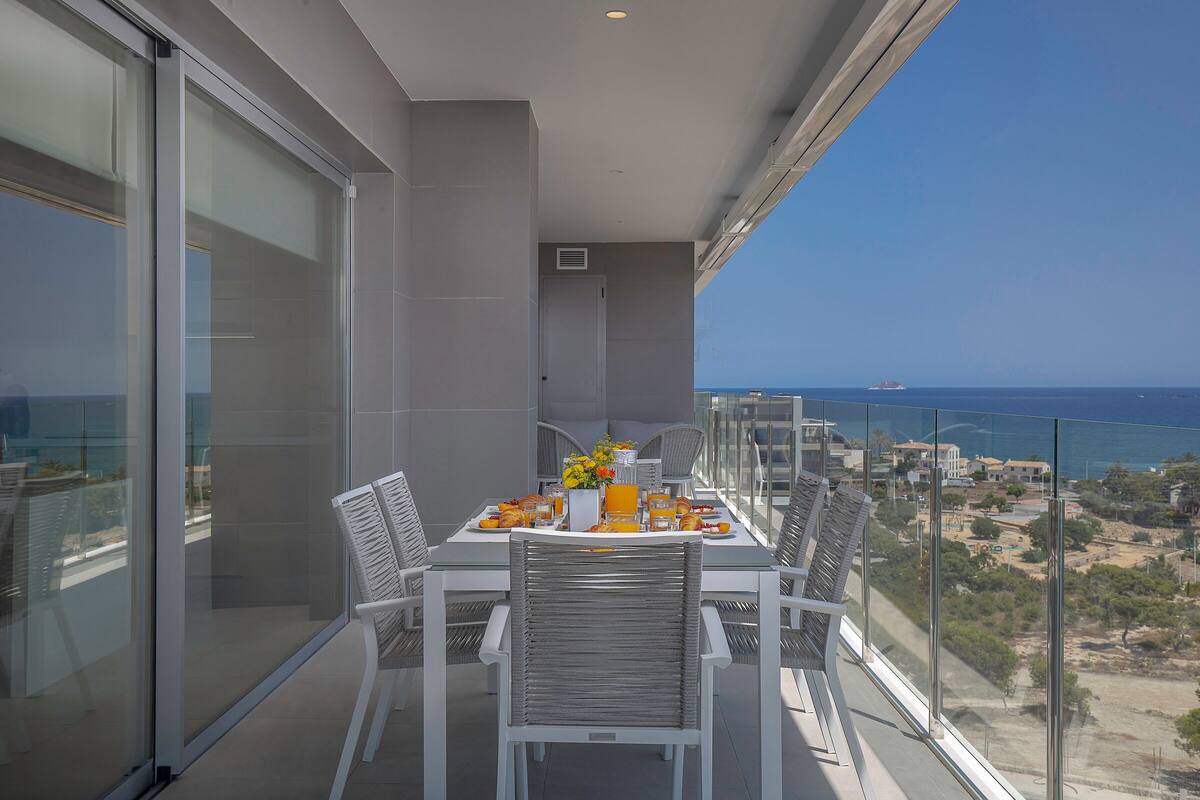 Ein Balkon mit Frühstückstisch, mit Blick auf die Küste.