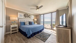 Ein Schlafzimmer mit Bett, Deckenventilator, Fernseher und Meerblick.