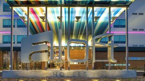 A hotel entrance with a modern design, featuring a large 'HOTELS' sign and a covered area with colorful lighting. - Aloft by Marriott North Kansas City (North Kansas City)