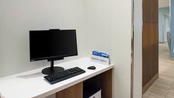 Un mostrador de recepción de hotel con computadora, teclado y ratón. Hay un cartel que indica el nombre del hotel.