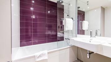 A modern bathroom with a glass shower enclosure, a white sink, and a large mirror.