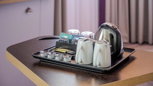 Una bandeja con tetera, tazas y sobre de té sobre una mesa de madera en una habitación de hotel.
