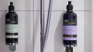 Dos botellas de jabón corporal Goodness sobre una pared.