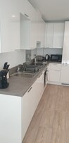 A modern kitchen with white cabinets, a stainless steel sink, a coffee maker, and a microwave.