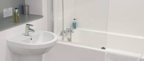 A modern bathroom with a white sink, toilet, and bathtub.