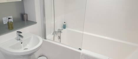 A bathroom with a white sink, a mirror, a shower enclosure, and a towel rack.