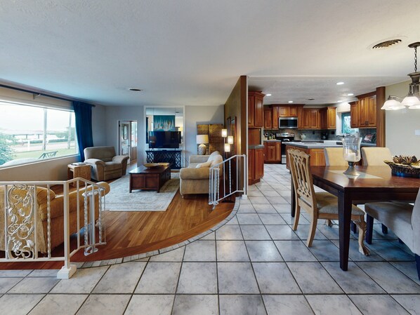 A spacious living area with a dining table, kitchen, and a balcony.