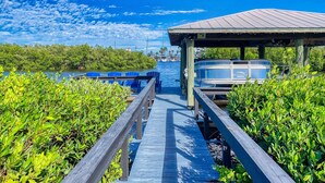 A wooden pier leading to a covered dock with a boat named "SMILE" and a marina with boats.