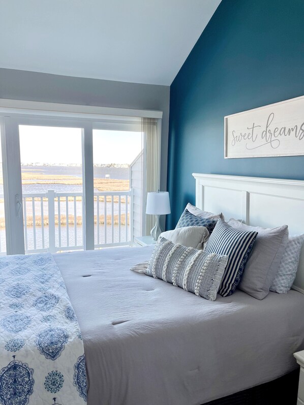 A bedroom with a large bed, a view of the outdoors, and a sign on the wall.
