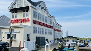Ein Gebäude mit einem Schild, auf dem „CATCH54 FISH HOUSE RAW BAR“ und „MARINE OFFICE“ steht.