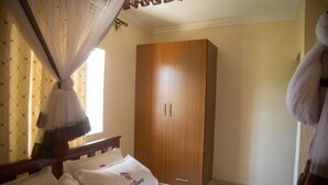 Une chambre à coucher avec un lit, une armoire en bois et une moustiquaire.
