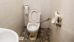 Une salle de bain équipée de toilettes, d’un bidet et d’un porte-rouleau de papier toilette.