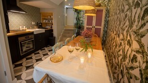 A modern kitchen with a dining area, featuring a large island, pendant lighting, and a staircase leading to an upper level.
