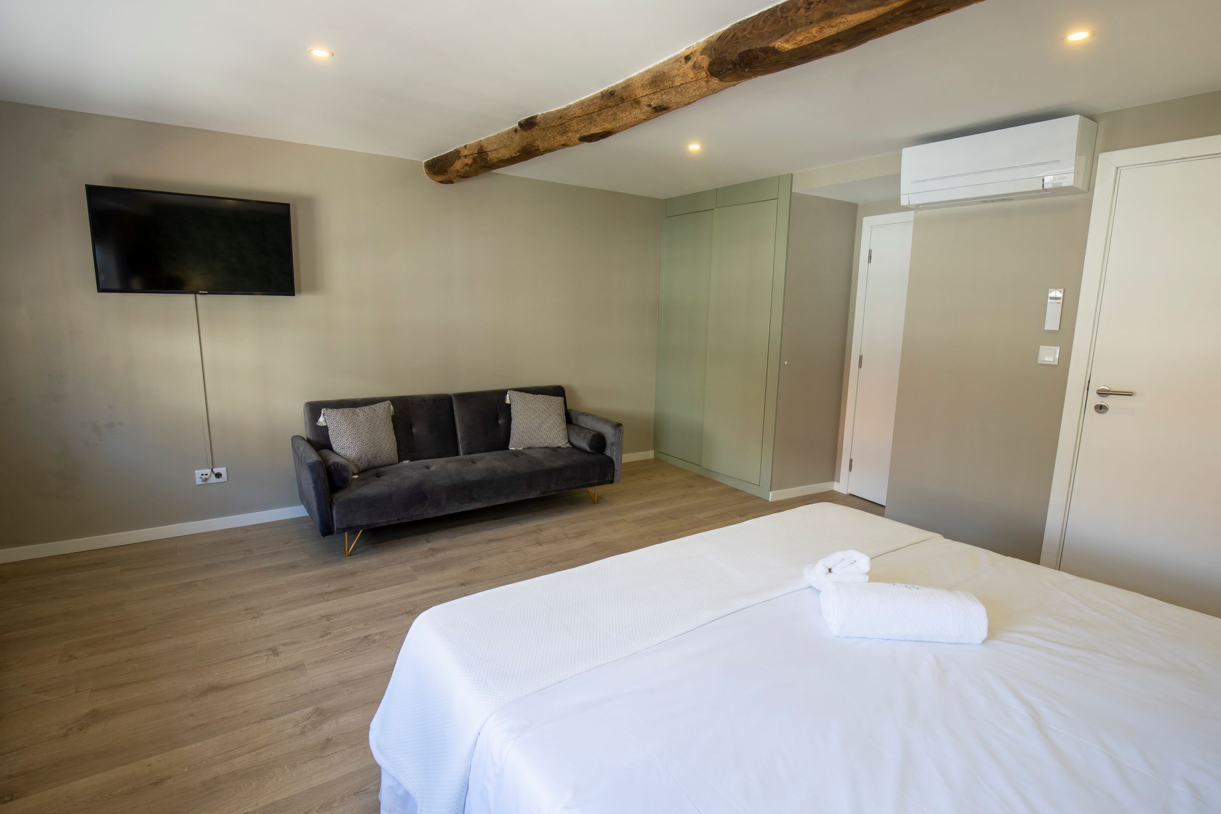 Un dormitorio con cama, sofá, televisor y aire acondicionado.