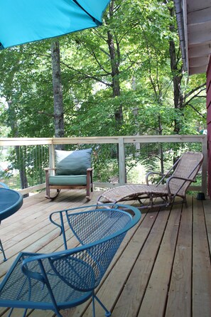 Relax on the deck with a view of the lush forest, surrounded by comfortable seating and a railing.