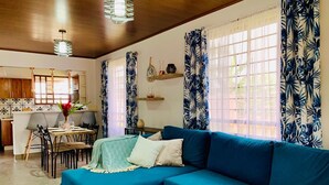 Un soggiorno con un divano modulare blu, un tavolo da pranzo con sedie e un'area cucina sullo sfondo.