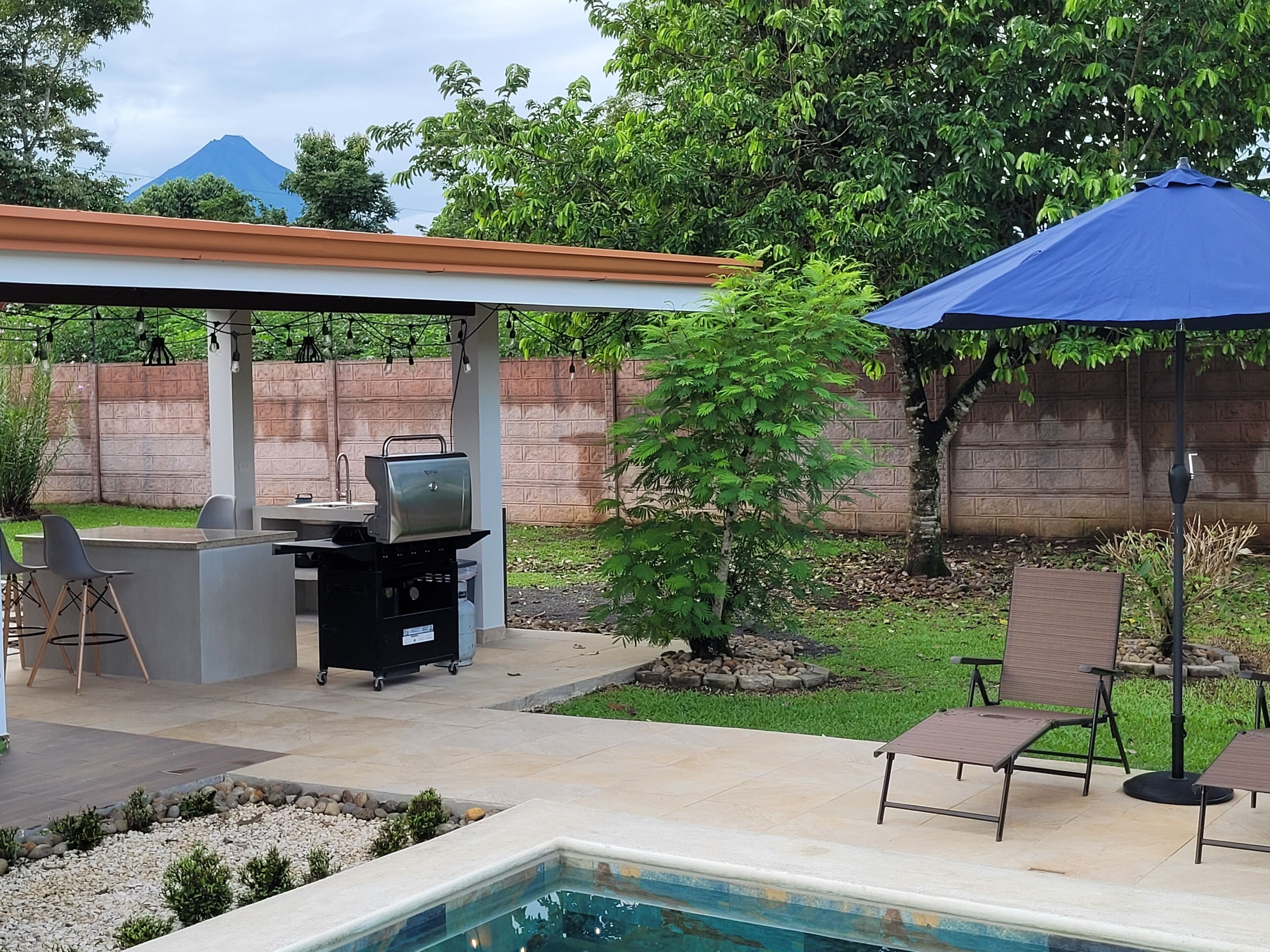 Un giardino sul retro con un barbecue, un'area relax esterna, una piscina e vista sulle montagne.