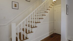 Un escalier avec des rampes blanches et des marches en bois, menant à une porte.