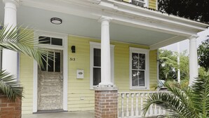 Une maison jaune, portant le numéro 313, avec un porche à l’avant orné de colonnes blanches et des fondations en briques.