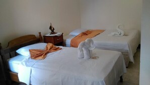 Quarto de hotel com duas camas, cada uma com roupa de cama branca e arranjo decorativo de toalhas.