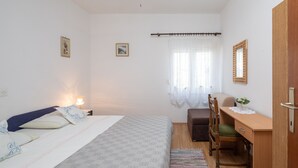 A bedroom with a bed, bedside table, chair, desk, and a window with curtains. - A1 - apt near beach with patio, parking and grill  (Stobreč)